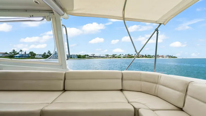 Slide: The Image of Spacious Aft Deck Seating Area This inviting aft deck features plush, wraparound seating, ideal for enjoying scenic views and socializing. The soft beige upholstery complements the yacht's elegant design, offering both comfort and style. Overhead, a protective canopy provides shade, en - 6479406