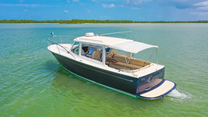 Slide: The Image of Aerial View of Camelot's Aft Deck This 2008 MJM 29z, named Camelot, showcases a spacious aft deck with comfortable seating, perfect for leisurely cruising. The vessel's elegant lines and sleek profile are enhanced by a protective canopy, providing shade and comfort. The swim platform at t - 6479379