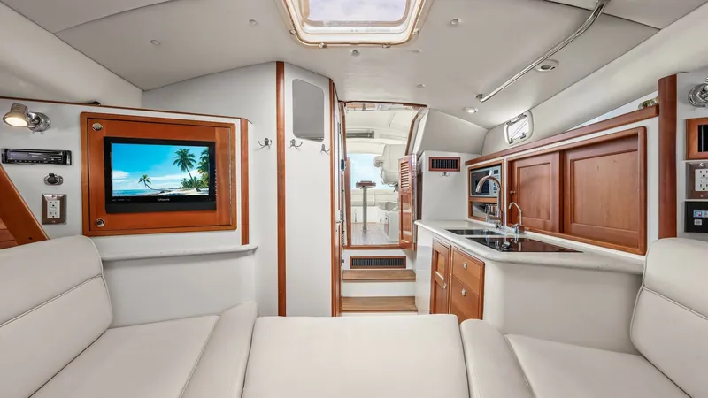 Slide: The Image of Interior Salon with Galley View The interior salon of the 2008 MJM Yachts 29z features a sleek and comfortable layout, combining elegant design with functionality. The space showcases plush seating, a flat-screen TV, and a well-equipped galley with wooden cabinetry and modern appliances - 6479370