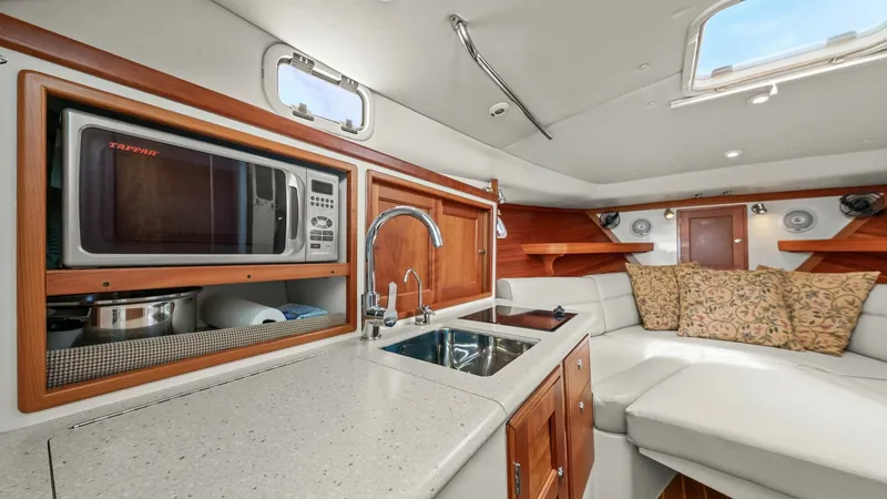 Slide: The Image of Galley and Salon Area This inviting galley and salon area of the 2008 MJM Yachts 29z features a sleek, modern design with high-quality finishes. The galley is equipped with a stainless-steel sink and a built-in microwave, complemented by rich wood cabinetry for ample storage. - 6479416