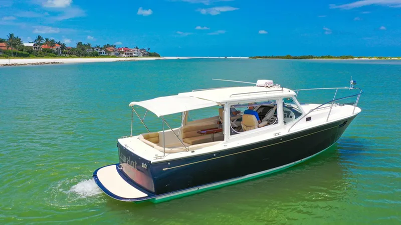 Slide: The Image of Aerial View of MJM 29z Camelot This aerial shot showcases the elegant MJM 29z Camelot gliding through serene waters. The vessel features a spacious aft deck with comfortable seating, perfect for leisurely cruising. Its sleek design and classic navy hull enhance its timeless appeal, whi - 6479375
