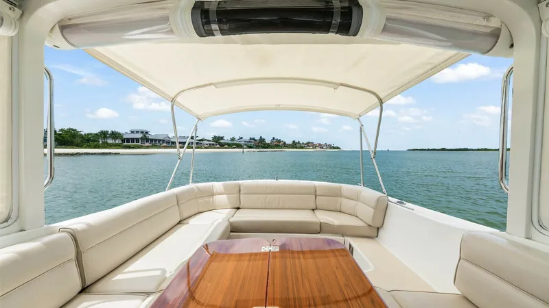 Slide: The Image of Aft Deck with Seating and Table The aft deck of the 2008 MJM Yachts 29z features a spacious U-shaped seating area upholstered in luxurious cream leather. A beautifully crafted wooden table serves as the centerpiece, perfect for alfresco dining or entertaining guests. The retractable can - 6479398