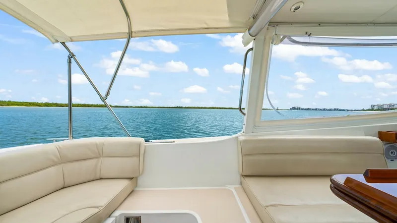 Slide: The Image of Spacious Aft Deck Seating Area This inviting aft deck on the MJM 29z features plush, cream-colored seating, perfect for social gatherings or relaxing cruises. The open layout provides stunning panoramic views, while the overhead canopy offers ample shade. The elegant teak accents and q - 6479407