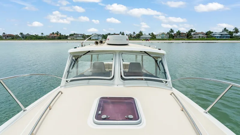 Slide: The Image of Foredeck with Cabin View This image showcases the sleek foredeck of the 2008 MJM Yachts 29z, featuring a prominent hatch for easy access to below deck areas. The expansive windshield provides excellent visibility and protection for the helm. The clean lines and stainless steel ra - 6479382