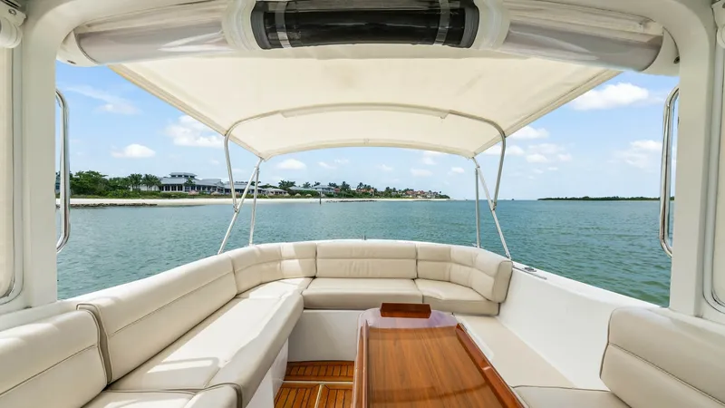 Slide: The Image of Spacious Aft Deck Seating Area The aft deck of the Camelot offers a luxurious and inviting seating area with plush, cream-colored upholstery. The space is accentuated by a beautifully crafted wooden table, perfect for social gatherings or alfresco dining. Overhead, a retractable canopy - 6479399