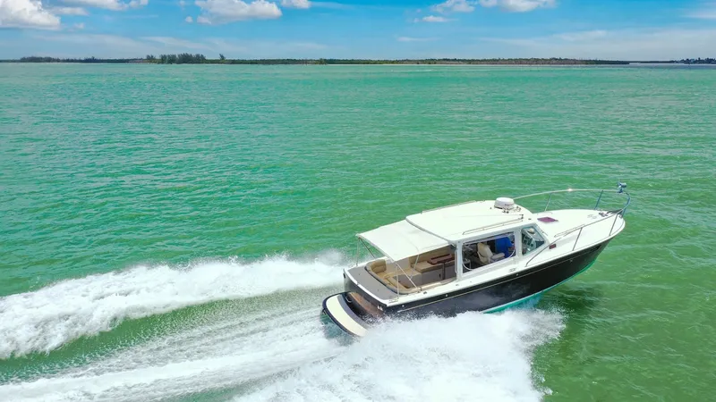 Slide: The Image of Aerial View of MJM 29z Underway The 2008 MJM 29z 'Camelot' glides smoothly over vibrant turquoise waters, showcasing its sleek design and efficient performance. The spacious cockpit is partially sheltered by a hardtop, providing comfort and versatility for open-air cruising. This vessel - 6479439