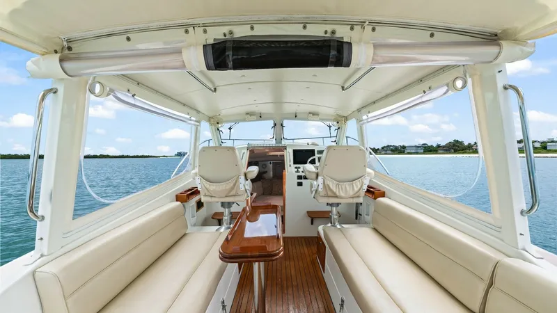 Slide: The Image of Spacious Cockpit with Seating Area The cockpit of the 2008 MJM Yachts 29z offers a comfortable and inviting space with plush, cream-colored seating on either side. The rich teak flooring adds a touch of elegance, while the central table provides practicality for social gatherings. Large wi - 6479395