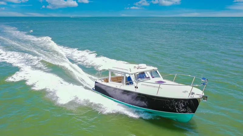 Slide: The Image of Aerial View of Camelot Cruising The MJM Yachts 29z, Camelot, gracefully cuts through the water, showcasing its sleek hull design and efficient performance. The vibrant blue and white color scheme complements the serene ocean backdrop, while the spacious cockpit ensures comfortable cruis - 6479438