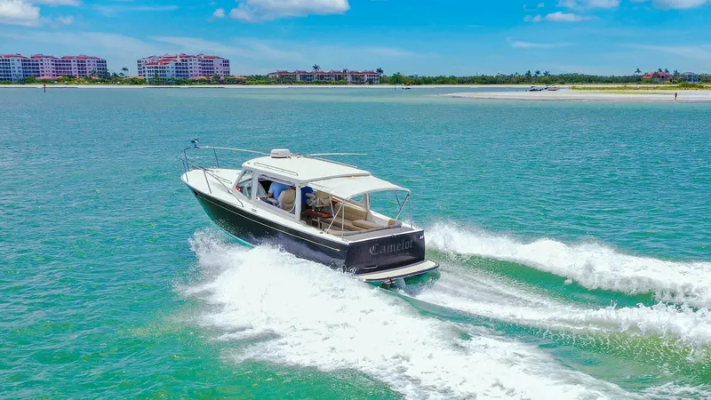 Slide: The Image of Aft View in Motion This image captures the sleek aft view of the 2008 MJM 29z Camelot cruising effortlessly through clear waters. The vessel's streamlined hull design and powerful engine create a striking wake, showcasing its impressive performance capabilities. The open co - 6479443