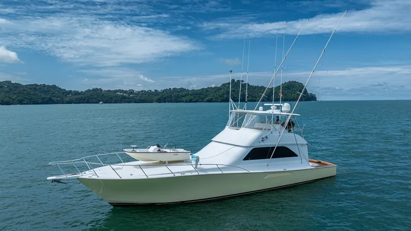 Slide: The Image of 2002 Viking 61 Convertible Exterior View This image showcases the sleek exterior of the 2002 Viking 61 Convertible, 'Bolita Too'. The yacht features a classic white hull with a spacious foredeck, perfect for sunbathing or storing watercraft. The flybridge is equipped with advanced fishing equipm - 6683675