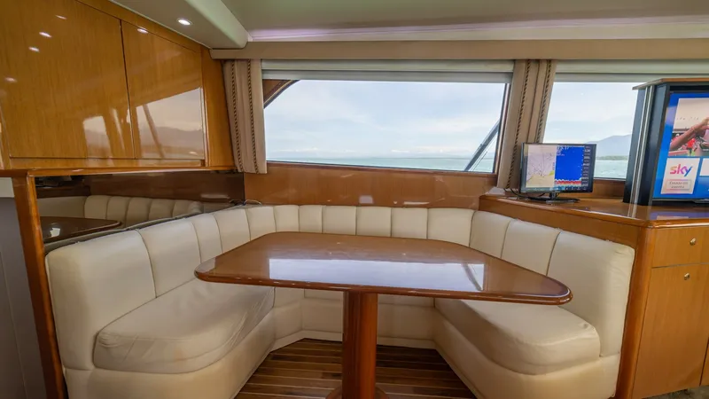Slide: The Image of Starboard Salon Dinette Area This inviting dinette area in the starboard salon of the 2002 Viking 61 Convertible features plush, cream-colored leather seating arranged in a cozy L-shape. The polished wood table complements the warm wood cabinetry, creating a sophisticated and comfort - 6683615