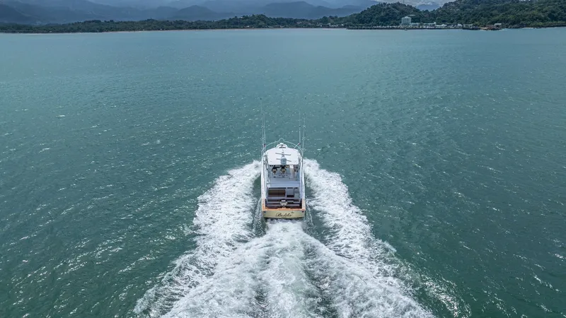 Slide: The Image of Aerial View of Stern Underway 2002 Viking 61 Convertible This dynamic aerial shot captures the Viking 61 Convertible 'Bolita Too' cruising confidently on open waters. The vessel's powerful wake showcases its robust engine performance and sleek hull design. The spacious aft deck is visible, offering ample space - 6683698