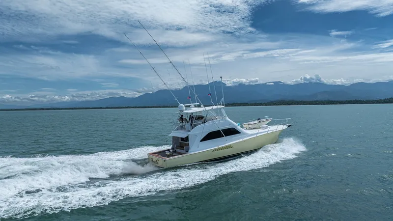 Slide: The Image of Aerial View of 2002 Viking 61 Convertible This dynamic aerial shot showcases the sleek profile of the 2002 Viking 61 Convertible, 'Bolita Too', cutting through open waters. The vessel's spacious flybridge and classic sportfishing lines are highlighted, emphasizing its powerful performance and ele - 6683689