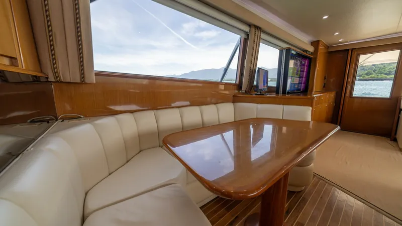 Slide: The Image of Salon Dining Area with Sea View This inviting salon dining area on the 2002 Viking 61 Convertible features a plush, L-shaped seating arrangement, perfect for leisurely meals or social gatherings. The elegant wooden table complements the warm tones of the cabinetry, creating a cozy yet s - 6683616