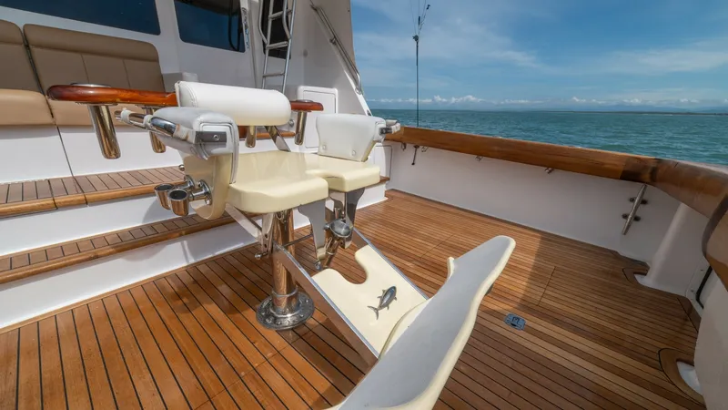 Slide: The Image of Teak Cockpit with Fighting Chair 2002 Viking 61 Convertible The cockpit of the 2002 Viking 61 Convertible features a luxurious teak deck, offering both durability and elegance. Central to this area is a professional fighting chair, ideal for sport fishing, surrounded by ample seating for relaxation or observation. - 6683645
