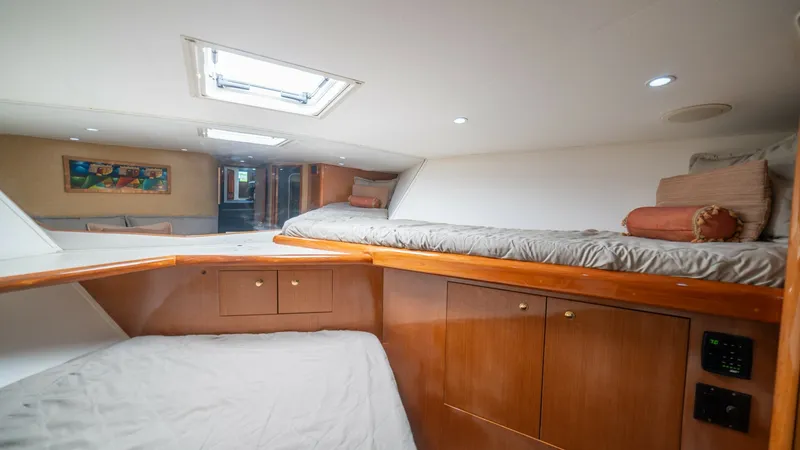 Slide: The Image of Forward VIP Stateroom 2002 Viking 61 Convertible This inviting guest cabin on the 2002 Viking 61 Convertible features twin berths, providing comfortable sleeping arrangements. The warm wood cabinetry adds a touch of elegance, complemented by soft lighting and an overhead hatch that brings in natural lig - 6683638