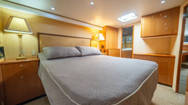 Slide: The Image of Master Stateroom 2002 Viking 61 Convertible The master stateroom of the 2002 Viking 61 Convertible, Bolita Too, offers a luxurious retreat with a plush queen-sized bed and elegant wood cabinetry. Soft ambient lighting and a skylight provide a warm and inviting atmosphere, complementing the sophisti - 6683629