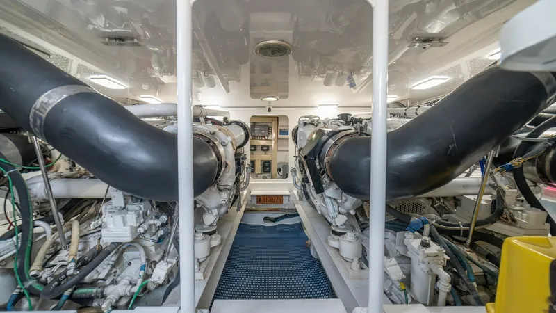Slide: The Image of Engine Room with Dual Engines 2002 Viking 61 Convertible The engine room of the Viking 61 Convertible showcases dual powerful engines, providing robust performance for the 2002 Bolita Too. The space is meticulously organized, with neatly arranged piping and wiring, ensuring easy access for maintenance. Bright o - 6683654