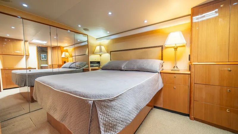 Slide: The Image of Master Stateroom with Mirrored Closet 2002 Viking 61 Convertible The master stateroom of the 2002 Viking 61 Convertible exudes warmth and elegance, featuring a spacious queen-sized bed with plush bedding. The room is beautifully illuminated with recessed lighting, complemented by elegant bedside lamps. Ample storage is - 6683612