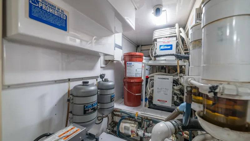 Slide: The Image of Engine Room with Equipment 2002 Viking 61 Convertible The engine room of the 2002 Viking 61 Convertible showcases a well-organized layout with essential equipment and storage. Prominent features include neatly arranged filters, tanks, and electrical components, ensuring efficient operation and maintenance. T - 6683659