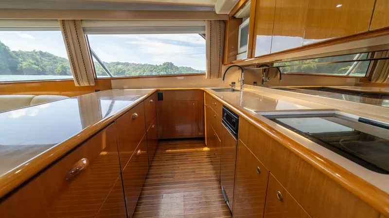 Slide: The Image of Galley with Panoramic Views This well-appointed galley on the 2002 Viking 61 Convertible features sleek wooden cabinetry and modern appliances, offering both functionality and style. Expansive windows provide stunning panoramic views, enhancing the open and airy atmosphere. The eleg - 6683618