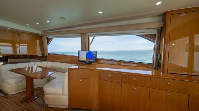Slide: The Image of Spacious Salon with Ocean Views The salon of the 2002 Viking 61 Convertible 'Bolita Too' features elegant wood cabinetry and a cozy L-shaped sofa. Large windows offer breathtaking ocean views, enhancing the open and airy feel of the space. The area is well-appointed with a mounted flat- - 6683614