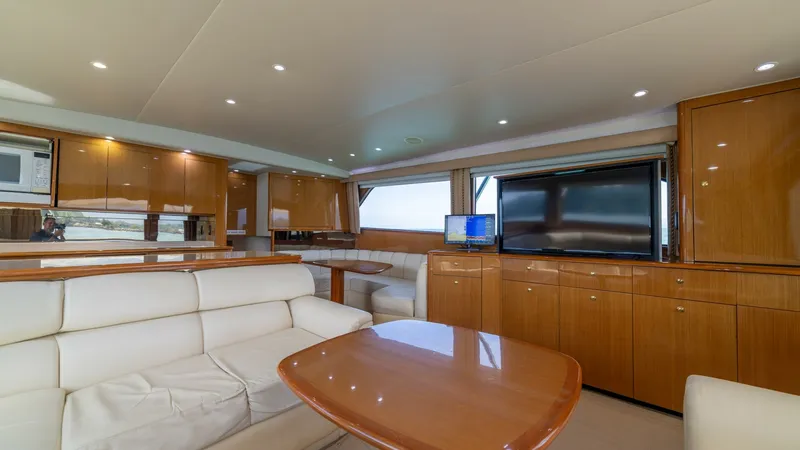 Slide: The Image of Salon/Galley 2002 Viking 61 Convertible The salon of the 2002 Viking 61 Convertible 'Bolita Too' features plush cream leather seating and a polished wooden coffee table, creating a warm and inviting space. A large flat-screen TV is mounted on the cabinetry, perfect for entertainment on the wate - 6683613