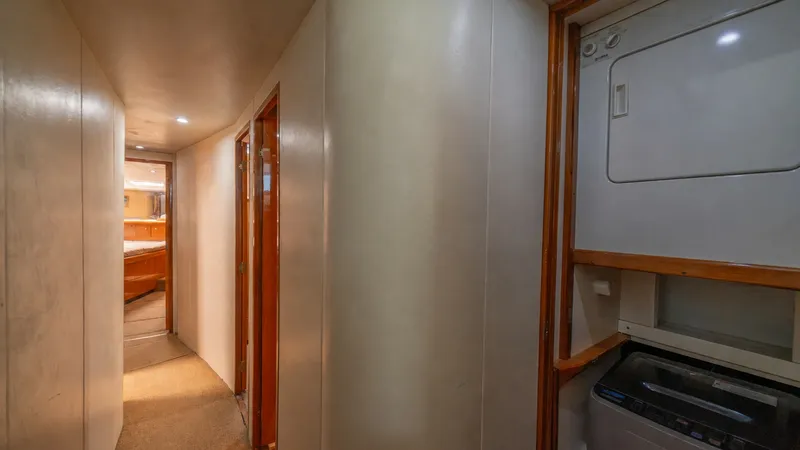 Slide: The Image of Hallway with Laundry Facilities 2002 Viking 61 Convertible This image showcases the hallway of the Viking 61 Convertible, featuring convenient onboard laundry facilities. The space is well-lit with recessed lighting, accentuating the seamless blend of practicality and comfort. The wood trim and soft carpeting add - 6683623