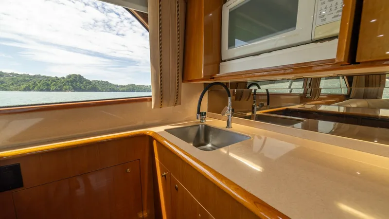 Slide: The Image of Galley with Scenic View The galley of the 2002 Viking 61 Convertible offers a sleek and functional space with polished wood cabinetry and a modern countertop. Equipped with a stainless steel sink and built-in microwave, it combines practicality with style. Large windows provide - 6683620