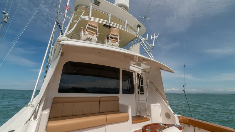 Slide: The Image of Cockpit and Flybridge View2002 Viking 61 Convertible This image showcases the aft deck of the 2002 Viking 61 Convertible, featuring a sleek, cushioned seating area ideal for relaxation. The flybridge above offers a commanding view, equipped with modern navigation equipment and comfortable helm chairs. The t - 6683653