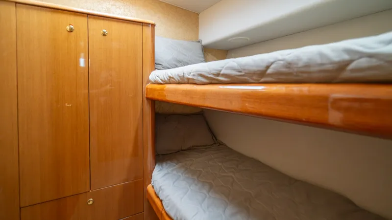 Slide: The Image of Guest Stateroom with Bunk Beds 2002 Viking 61 Convertible This cozy guest stateroom features twin bunk beds, offering comfortable accommodation for additional passengers. The warm wood finishes on the cabinetry and the bunks add a touch of elegance and warmth to the space. Ample storage is provided by the built- - 6683626