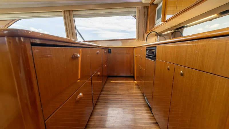 Slide: The Image of Galley with Ample Storage Space This well-appointed galley aboard the 2002 Viking 61 Convertible features rich wooden cabinetry and sleek countertops, providing both style and functionality. The ample storage space is complemented by modern appliances, ensuring a seamless cooking experi - 6683617