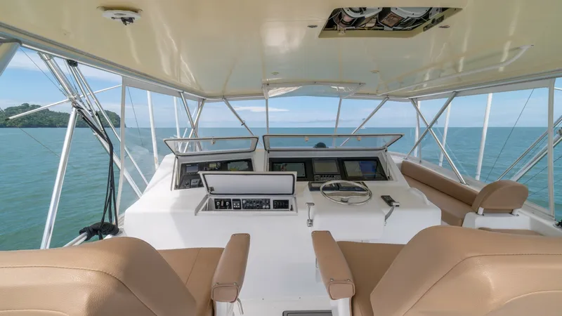 Slide: The Image of Flybridge Helm Station 2002 Viking 61 Convertible The flybridge of the 2002 Viking 61 Convertible offers a commanding helm station equipped with advanced navigation instruments. The spacious seating area features plush, tan upholstery, ensuring comfort while navigating the open waters. Surrounded by pano - 6683610
