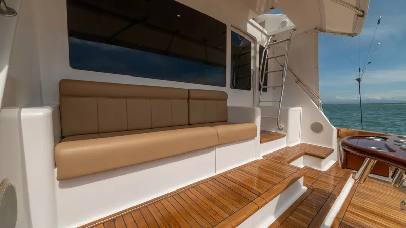 Slide: The Image of Spacious Cockpit with Teak Flooring 2002 Viking 61 Convertible The aft deck of the 2002 Viking 61 Convertible features elegant teak flooring, offering durability and a classic aesthetic. A plush upholstered bench provides comfortable seating, ideal for socializing while enjoying the ocean views. The well-integrated l - 6683648