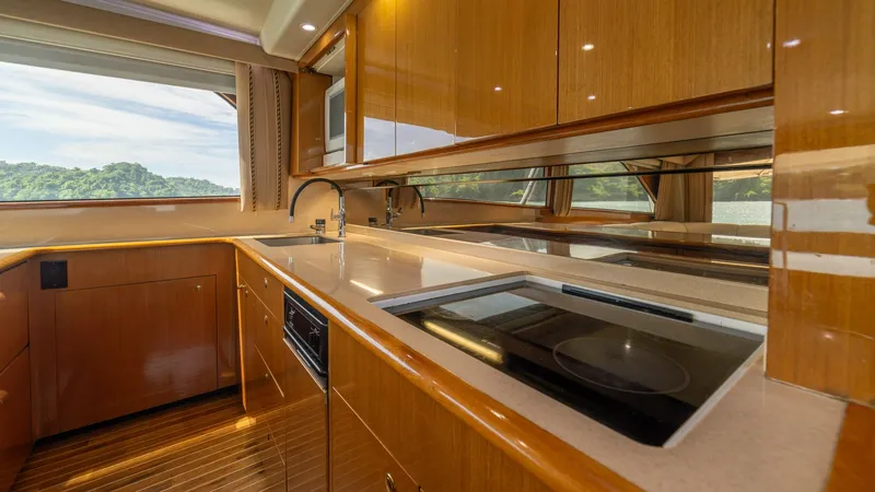 Slide: The Image of Galley with Modern Appliances This well-appointed galley features sleek cabinetry and modern appliances set against a backdrop of rich wood finishes. The large windows provide ample natural light and stunning views, enhancing the spacious feel. The layout includes a smooth countertop - 6683619