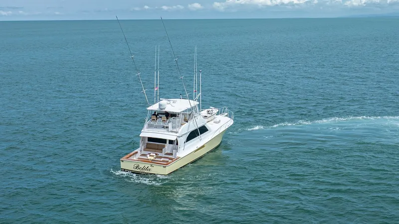 Slide: The Image of Aerial Stern View of 2002 Viking 61 Convertible This image showcases the elegant stern of the 2002 Viking 61 Convertible, 'Bolita Too', gracefully navigating open waters. The spacious aft deck is designed for both relaxation and sportfishing, equipped with sturdy rod holders and a comfortable seating a - 6683680