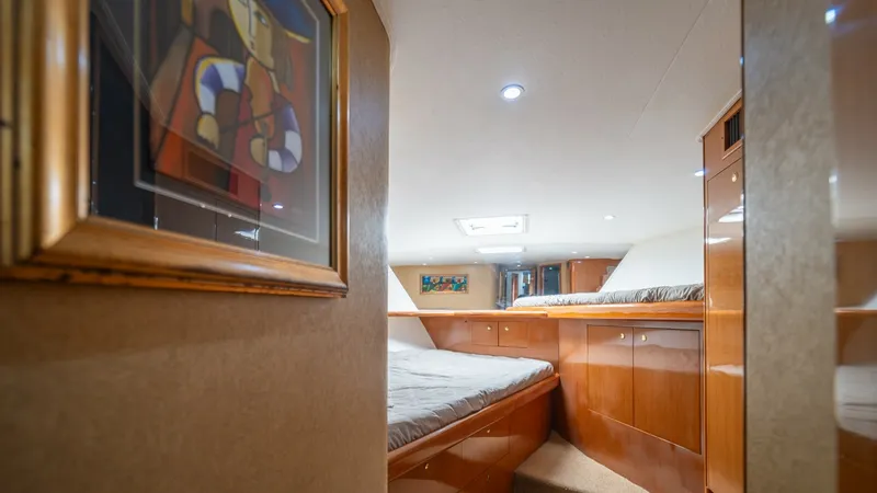 Slide: The Image of Forward VIP Stateroom with Twin Berths Master Bathroom with Shower 2002 Viking 61 Convertible This inviting guest stateroom on the Viking 61 Convertible features twin berths with plush bedding, perfect for comfortable overnight stays. The space is adorned with warm wood cabinetry, offering ample storage and a touch of elegance. Soft, recessed ligh - 6683636