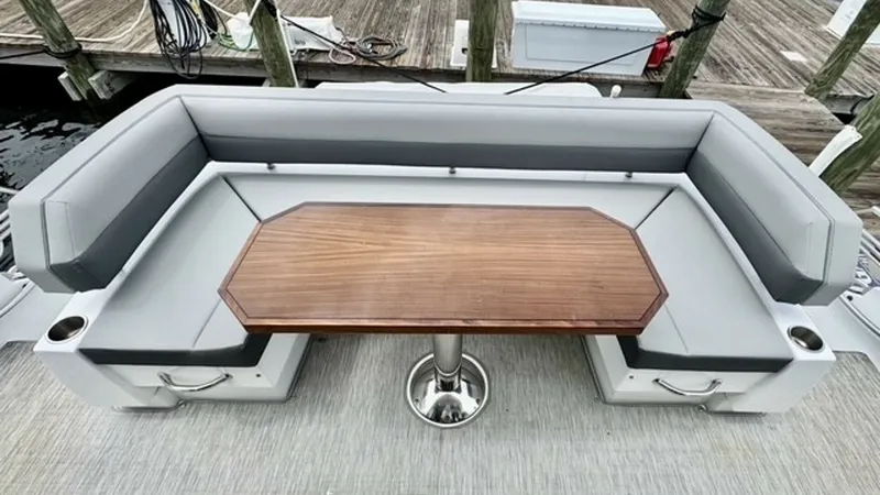 Slide: The Image of Aft Deck Seating with Table This image showcases the aft deck seating area of the 2023 Cruisers Yachts 50 Cantius. It features a spacious, U-shaped cushioned bench surrounding a beautifully crafted wooden table, perfect for social gatherings or relaxing with a view. The design empha - 6489159
