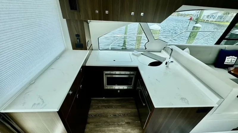 Slide: The Image of Galley with Marble Countertops This stylish galley on the 2023 Cruisers Yachts 50 Cantius features elegant marble countertops and modern wood cabinetry. Equipped with a built-in microwave and a sleek sink, the space is designed for both functionality and aesthetics. Large windows provi - 6489142