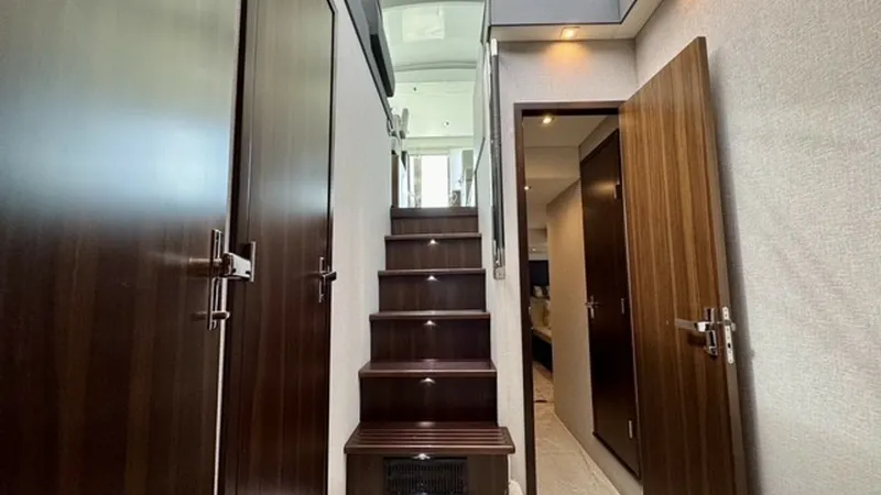 Slide: The Image of Interior Stairway with Wood Paneling This image showcases the elegant interior stairway of the 2023 Cruisers Yachts 50 Cantius. The stairs are beautifully crafted with rich, dark wood paneling, complemented by soft LED lighting that guides the way. The surrounding walls and doors exude a lux - 6489149