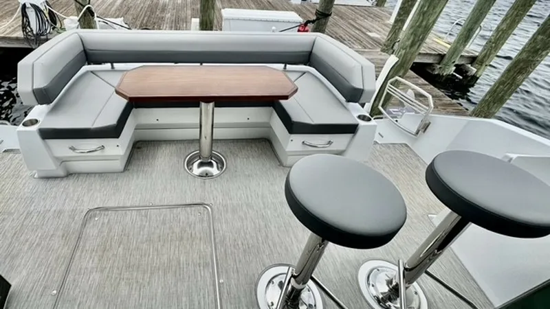 Slide: The Image of Spacious Aft Deck Seating Area The aft deck of the 2023 Cruisers Yachts 50 Cantius features a stylish and comfortable seating arrangement with a sleek wooden table at the center. The L-shaped cushioned seating invites relaxation and socializing, while the two pedestal bar stools add ve - 6489160