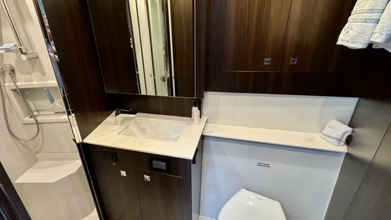 Slide: The Image of Elegant Ensuite Bathroom This sophisticated ensuite bathroom on the 2023 Cruisers Yachts 50 Cantius features sleek dark wood cabinetry and a pristine white countertop. The space is equipped with a modern sink, ample storage, and a separate shower area, providing both functionalit - 6489154