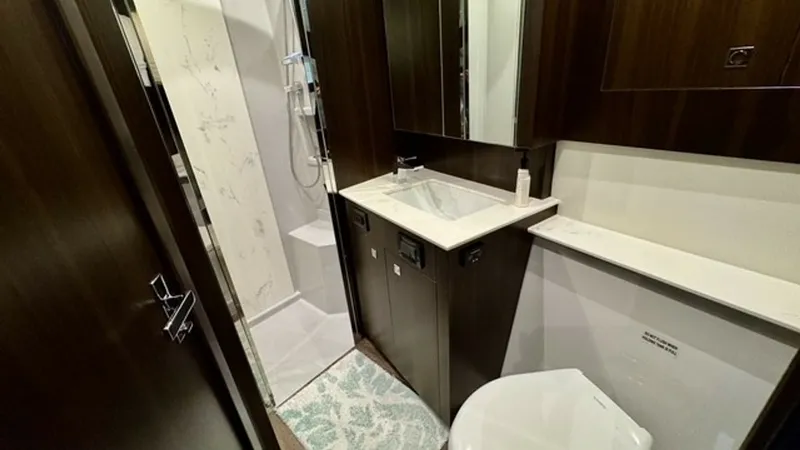 Slide: The Image of Elegant Ensuite Bathroom This sophisticated ensuite bathroom on the 2023 Cruisers Yachts 50 Cantius features a contemporary design with dark wood cabinetry and sleek white countertops. The space offers a modern shower with a glass enclosure and stylish fixtures, providing both fu - 6489153