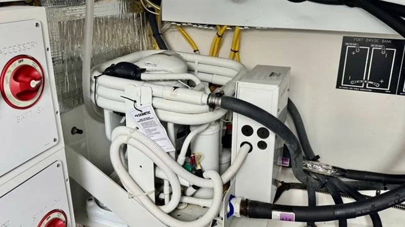 Slide: The Image of Engine Room Systems and Wiring This image showcases the organized engine room systems of the 2023 Cruisers Yachts 50 Cantius. Highlighted are the neatly arranged hoses and electrical wiring, demonstrating meticulous attention to detail and engineering. The control panel and labeled com - 6489163