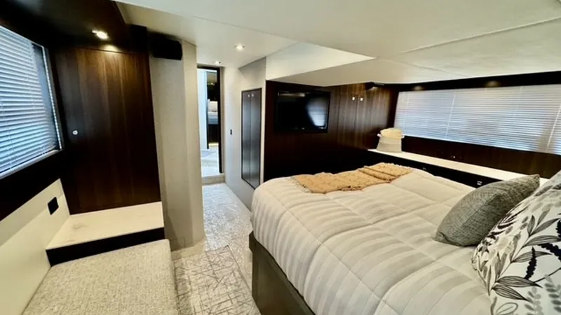 Slide: The Image of Master Stateroom with Luxurious Amenities The master stateroom of the 2023 Cruisers Yachts 50 Cantius showcases elegant design with rich wood finishes and plush bedding. A large window provides natural light, enhancing the spacious feel, while modern lighting fixtures add a touch of sophisticatio - 6489150