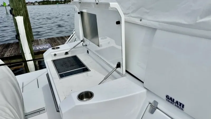 Slide: The Image of Transom Grill and Prep Station This image showcases the transom grill and prep station on the 2023 Cruisers Yachts 50 Cantius. The sleek design features a built-in grill with a hinged cover, perfect for outdoor cooking and entertaining. Stainless steel cup holders and ample counter spa - 6489156