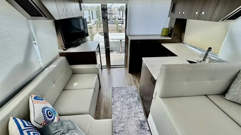 Slide: The Image of Contemporary Interior Salon with Galley The interior salon of the 2023 Cruisers Yachts 50 Cantius features a sleek, modern design with plush seating and a well-equipped galley. Large windows allow for abundant natural light, enhancing the sense of space and openness. The area is perfect for ent - 6489136