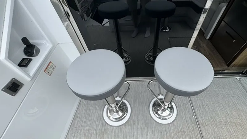 Slide: The Image of Cockpit Seating Area with Bar Stools This image showcases the sleek cockpit area of the 2023 Cruisers Yachts 50 Cantius. Featuring two stylish bar stools with polished metal bases and plush gray cushions, this space is designed for casual relaxation and socializing. The sophisticated finishe - 6489158
