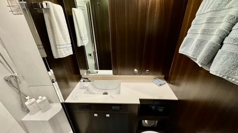 Slide: The Image of Luxurious Bathroom Vanity Area This elegant bathroom on the 2023 Cruisers Yachts 50 Cantius features a sleek vanity with a modern sink and ample storage. Rich wood paneling and a mirrored cabinet enhance the luxurious feel, while soft towels add a touch of comfort. The contemporary des - 6489151