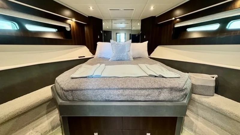 Slide: The Image of Luxurious Forward Stateroom The forward stateroom of the 2023 Cruisers Yachts 50 Cantius showcases a plush, centrally positioned bed flanked by stylish wood paneling and ambient lighting. The space is enhanced by elongated side windows that offer natural light and a panoramic view. - 6489152